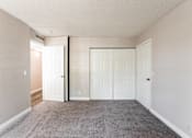 Thumbnail 10 of 20 - A room with white doors and carpeted floor.
