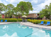 Thumbnail 15 of 20 - swimming pool with patio table and lounge chairs at Timberfalls Apartments