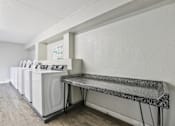 Thumbnail 16 of 21 - A laundry room with a washer and dryer on the left and a bench on the right.