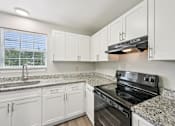 Thumbnail 1 of 55 - A kitchen with white cabinets and granite countertops.
