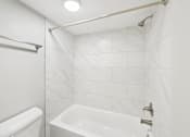 Thumbnail 19 of 55 - A white bathroom with a tub, toilet and shower.