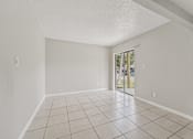 Thumbnail 34 of 39 - A room with white walls and tiled flooring with a sliding glass door.
