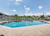 Thumbnail 27 of 31 - A swimming pool surrounded by a concrete patio and a metal fence.