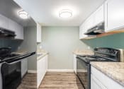 Thumbnail 6 of 19 - a kitchen with white cabinets and black appliances at Bella Mar Apartments