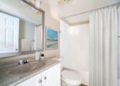 Thumbnail 9 of 13 - A bathroom with a toilet, sink, and shower.