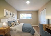 Thumbnail 6 of 13 - A bedroom with a bed, desk, and chair.