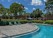 Thumbnail 14 of 21 - A swimming pool surrounded by a brick patio and lawn chairs.