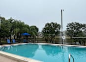 Thumbnail 13 of 13 - A pool with a blue umbrella and a black fence.