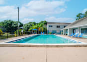 Thumbnail 12 of 13 - A swimming pool in front of a building with a fence around it.