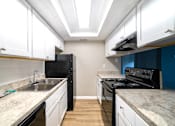 Thumbnail 4 of 13 - A kitchen with black appliances and white cabinets.