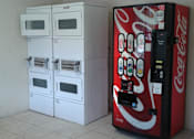 Thumbnail 9 of 12 - A Coca-Cola vending machine is to the right of a row of white microwaves.