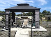 Thumbnail 12 of 12 - A gazebo with a black roof is surrounded by a black fence.