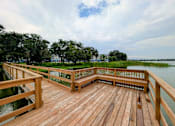 Thumbnail 28 of 35 - A wooden deck overlooks a body of water with a green landscape in the background.