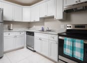 Thumbnail 3 of 33 - a kitchen with white cabinets and black and silver appliances at Fairways of Inverrary, Lauderhill, FL