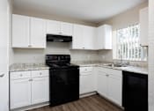 Thumbnail 2 of 31 - A kitchen with black appliances and white cabinets.