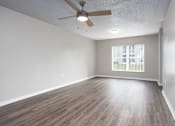 Thumbnail 6 of 31 - A room with a ceiling fan and wooden flooring.