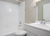 Thumbnail 15 of 31 - A white toilet sits next to a white sink in a bathroom.