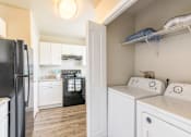 Thumbnail 3 of 31 - A black refrigerator is in a kitchen with white cabinets.