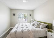 Thumbnail 7 of 31 - A bedroom with a large bed and a window overlooking a street.