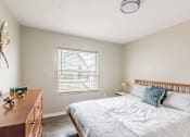 Thumbnail 9 of 31 - A bedroom with a bed, nightstand, and window with blinds.