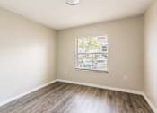 Thumbnail 13 of 31 - A room with a window and wooden flooring.