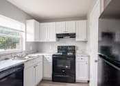 Thumbnail 1 of 31 - A kitchen with black appliances and white cabinets.