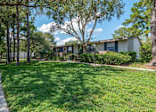Thumbnail 17 of 21 - A grassy area with a walking path and trees in front of a building.
