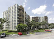 Thumbnail 29 of 33 - A large apartment building with a parking lot in front.