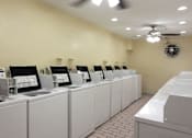 Thumbnail 23 of 33 - A row of washing machines are lined up in a laundromat.