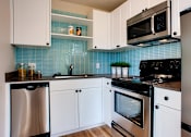 Thumbnail 11 of 16 - a kitchen with white cabinets and a stove and a sink