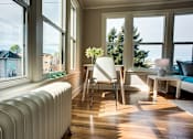 Thumbnail 10 of 16 - a living room with a radiator and a table with a chair