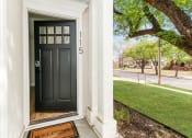 Thumbnail 3 of 18 - a front porch with a black door and a tree with green grass