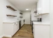 Thumbnail 8 of 18 - a kitchen with white cabinetry and a wood floor