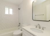 Thumbnail 10 of 18 - a bathroom with white tiles and a white sink and toilet