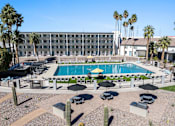 Thumbnail 92 of 96 - A pool surrounded by chairs and umbrellas with a building in the background at Presidio Palms Apartments, Tucson, AZ, 85701