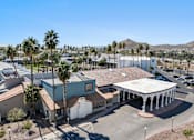 Thumbnail 93 of 96 - A building with a white roof and a covered patio is surrounded by palm trees at Presidio Palms Apartments, Tucson, AZ