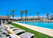 Thumbnail 42 of 95 - a resort style pool with white chairs and palm trees at Presidio Palms Apartments, Tucson