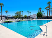 Thumbnail 48 of 95 - a swimming pool with palm trees and a building in the background at Presidio Palms Apartments, Arizona, 85701