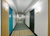 Thumbnail 77 of 95 - A long hallway with doors on both sides and a striped wall on the right at Presidio Palms Apartments, Arizona, 85701