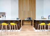 Thumbnail 40 of 95 - a cafe with yellow chairs and marble counters and wood floors at Presidio Palms Apartments, Arizona, 85701