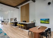 Thumbnail 46 of 95 - a resident gathering area with a wooden table and chairs and a bar with yellow chairs at Presidio Palms Apartments, Tucson