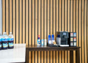 Thumbnail 39 of 95 - a counter with a coffee machine and water bottles at Presidio Palms Apartments, Tucson, Arizona