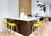 Thumbnail 47 of 95 - a bar with yellow chairs and a marble counter in a restaurant at Presidio Palms Apartments, Arizona