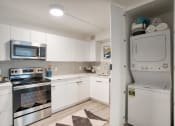 Thumbnail 23 of 95 - a white kitchen with stainless steel appliances and white cabinets at Presidio Palms Apartments, Arizona