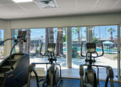 Thumbnail 51 of 95 - a gym with cardio machines and a view of a pool at Presidio Palms Apartments, Arizona, 85701
