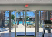 Thumbnail 55 of 95 - a view of a swimming pool from a gym with glass doors at Presidio Palms Apartments, Tucson, AZ