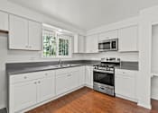 Thumbnail 14 of 27 - A kitchen with white cabinets and a stainless steel oven.