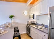 Thumbnail 22 of 28 - A kitchen with white cabinets and stainless steel appliances.