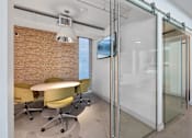 Thumbnail 15 of 31 - A conference room with a glass wall and yellow chairs.