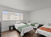 Thumbnail 15 of 28 - Three beds with white bedspreads and green and brown blankets in a room with wooden floors.
